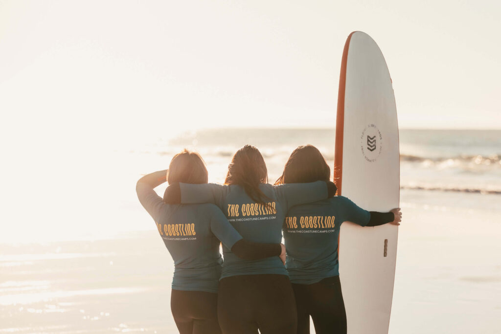 The Coastline Camps three girls huging after a surf lesson at the beach